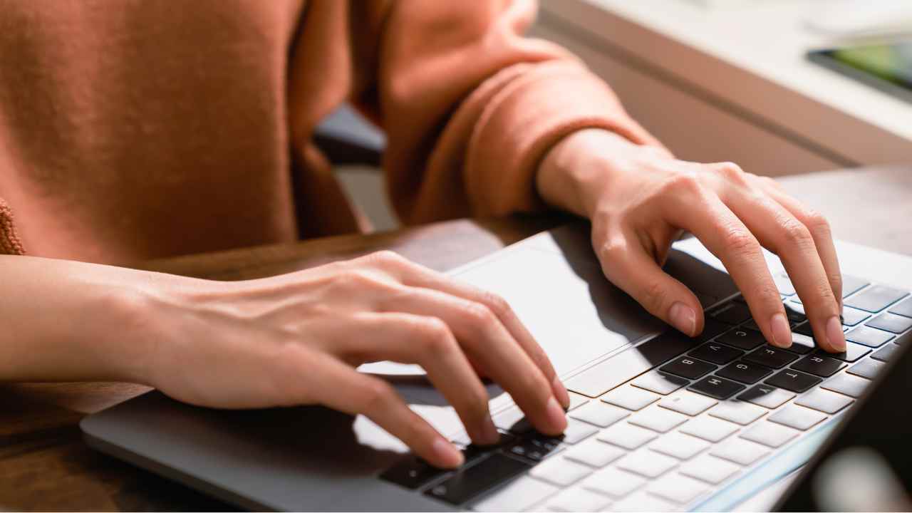 Hands typing on laptop keyboard in workplace
