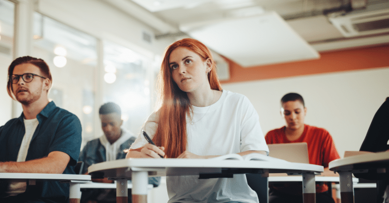 A high school student balancing test prep books and extracurricular activities on a desk.